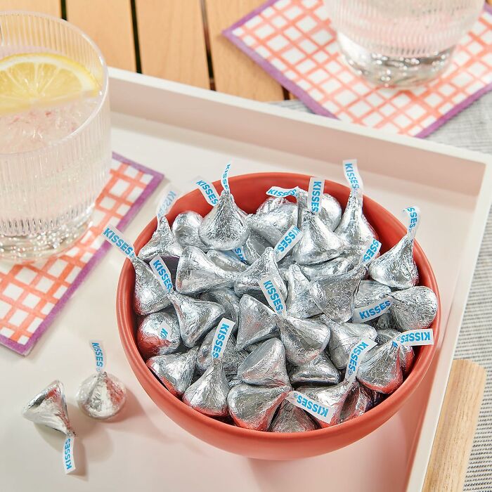 A terracotta bowl filled with silver wrapped Hershey Kisses, iconic Halloween Candies for treats