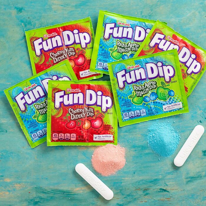 Pouches of Fun Dip candy with edible sticks and candy powder on a turquoise background for Best Halloween Candies.