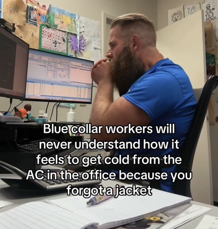 Man at desk cold from office air conditioning with text about blue collar workers and financial dystopia