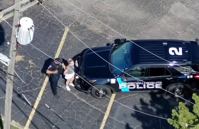 Police officer arresting woman next to police car Police officer arresting woman next to police car