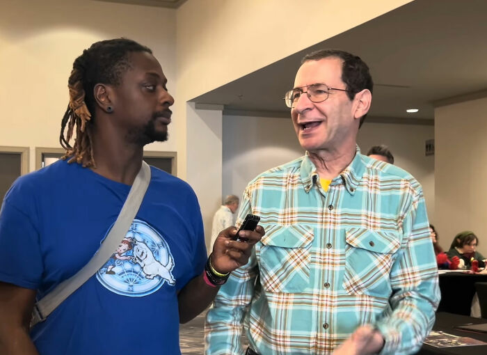 Grease actor talking with another man, raising questions about how men lack self-awareness.