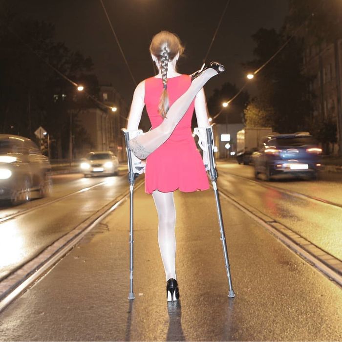 Woman with a leg amputation on crutches poses outdoors in a red dress for Halloween.