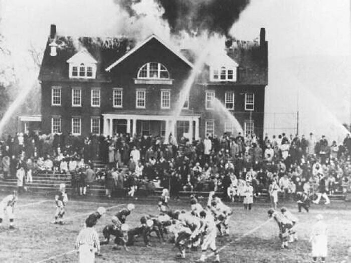 А High School Footbаll Game Continues As A Fire Rages On At A School In Northfield, Massachusetts. 1965