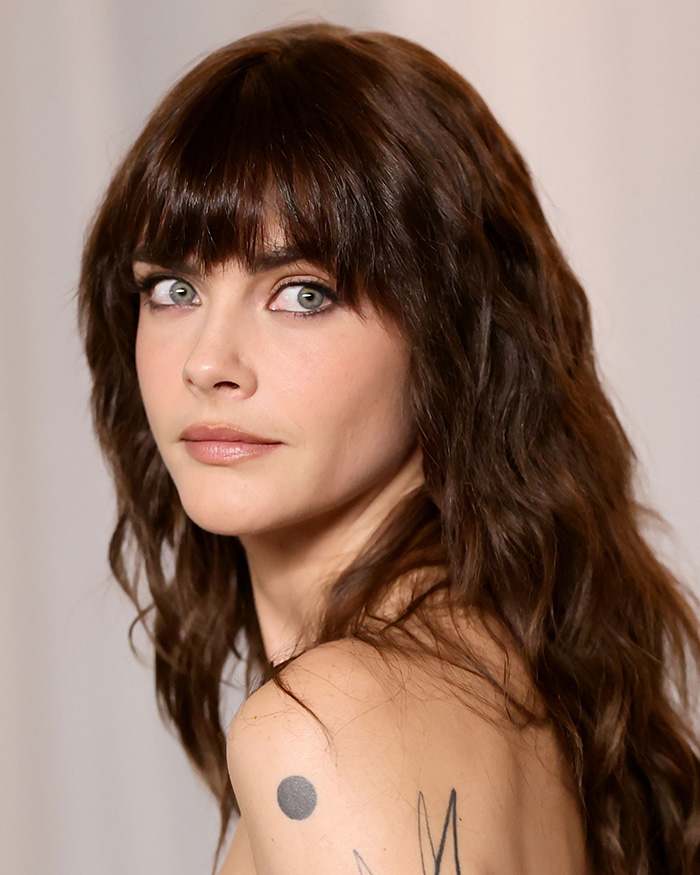 Unedited photo of Cara Delevingne showcasing dark wavy hair with bangs at the Academy Museum Gala.