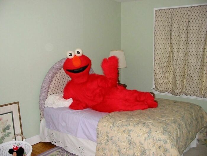 Cursed image of person in Elmo costume lounging on bed
