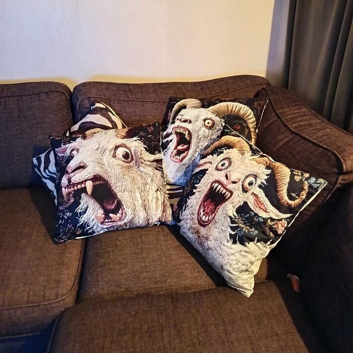 A couch covered in throw pillows printed with creepy photos of screaming goat faces.