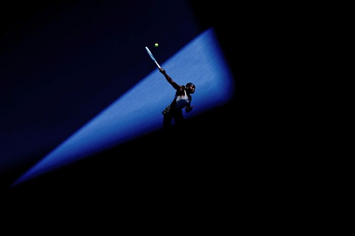Tennis player serving spotlighted on dark background, best pics 2026 Siena International Photo Awards