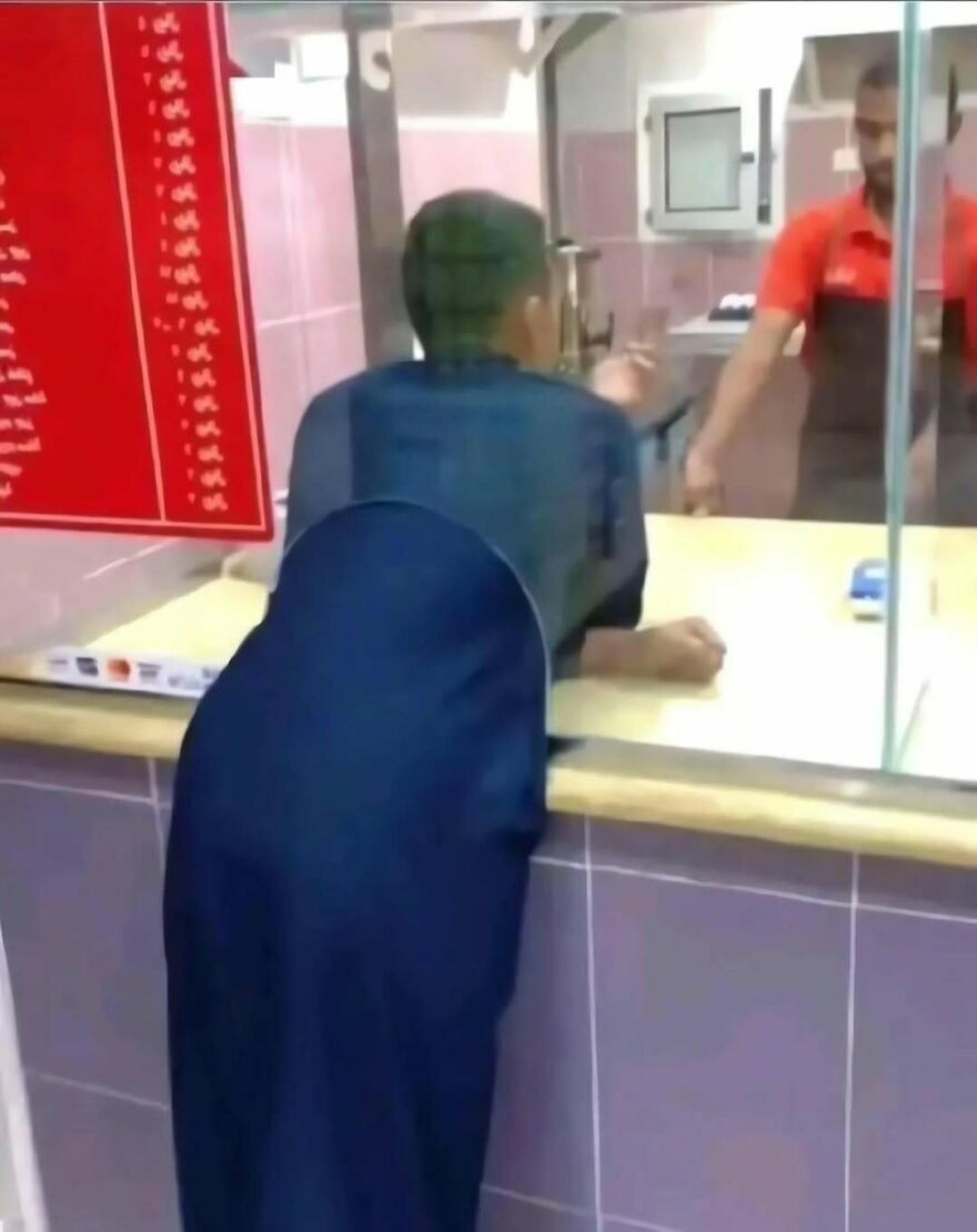 A funny out-of-context pics moment of a customer leaning over a counter in a confusing perspective.