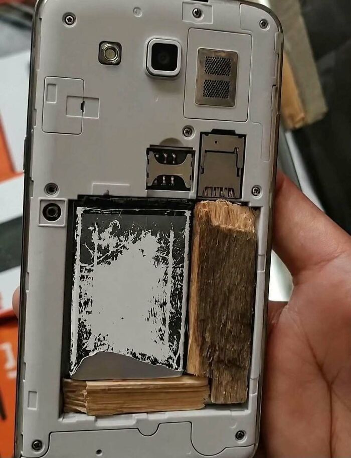 A questionable DIY project featuring a mobile phone battery held in place with rough blocks of wood