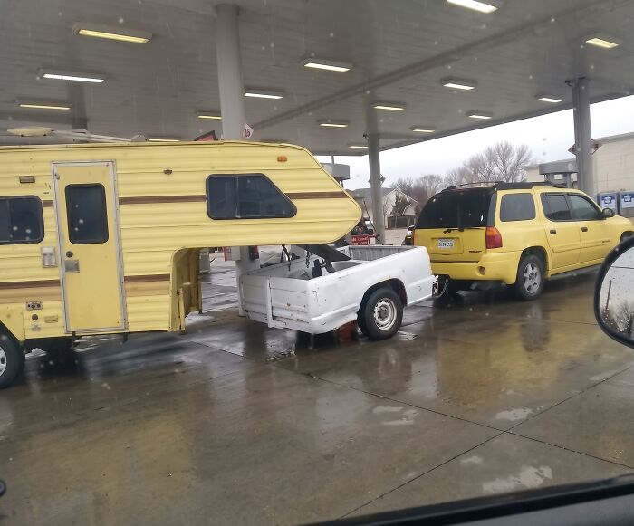 A yellow SUV towing a detached pickup truck bed carrying a camper trailer in an example of towing gone wrong.