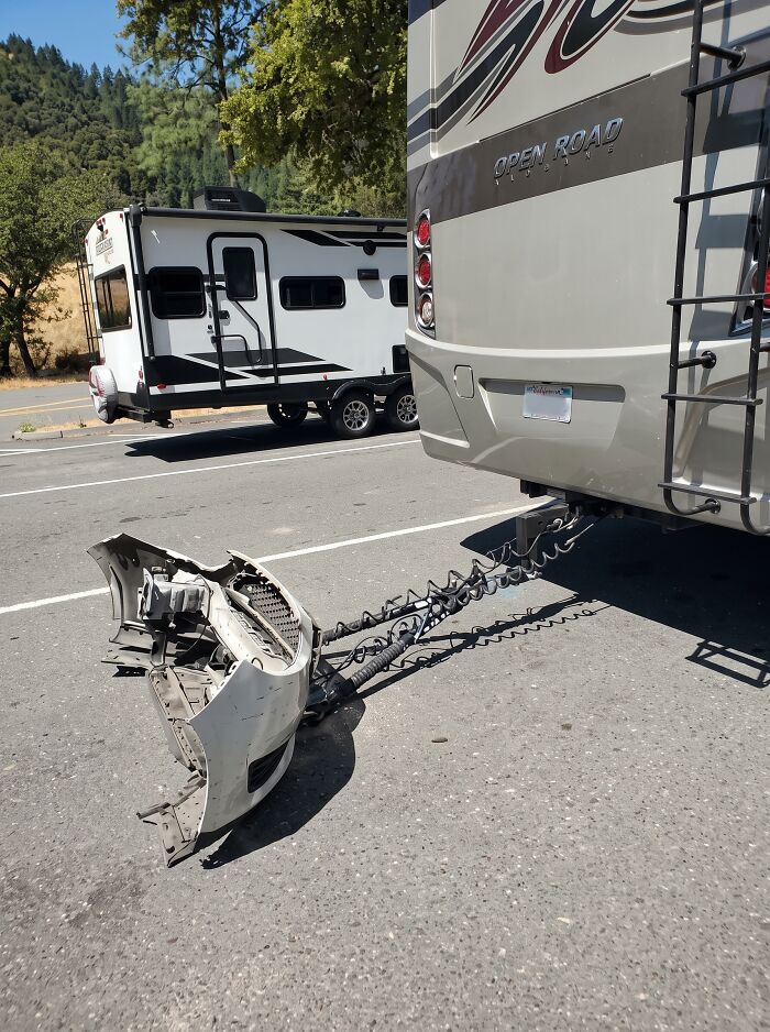 RV towing only the detached front bumper of a car, showcasing towing gone wrong.