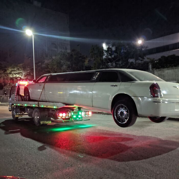 An example of towing gone wrong featuring a long white limousine hanging off the back of a flatbed tow truck.