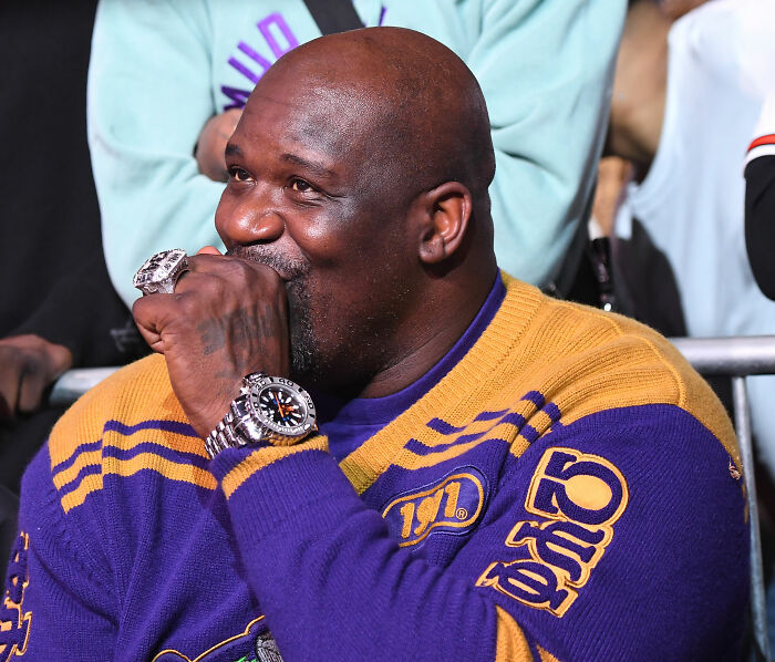 Shaquille O'Neal smiling and covering his mouth at an event Shaquille O'Neal smiling and covering his mouth at an event