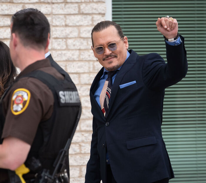 Johnny Depp waving outside a courtroom during the Amber Heard lawsuit high-profile trial