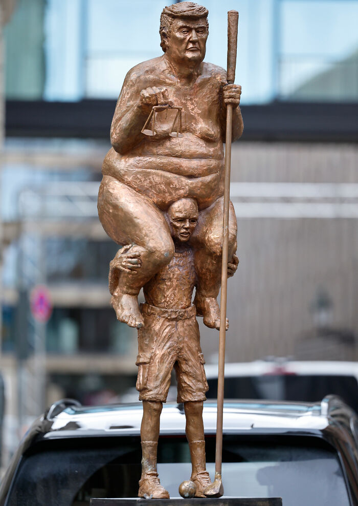 A satirical golden statue of Donald Trump depicted naked and sitting on someone’s shoulders. A satirical golden statue of Donald Trump depicted naked and sitting on someone’s shoulders.