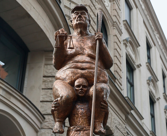 Close-up of a satirical golden statue of Donald Trump depicting him sitting on a man's shoulders. Close-up of a satirical golden statue of Donald Trump depicting him sitting on a man's shoulders.