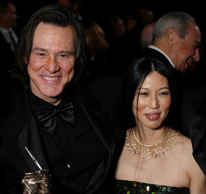 Jim Carrey standing next to his girlfriend Min Ah at an event, both smiling. Jim Carrey standing next to his girlfriend Min Ah at an event, both smiling.