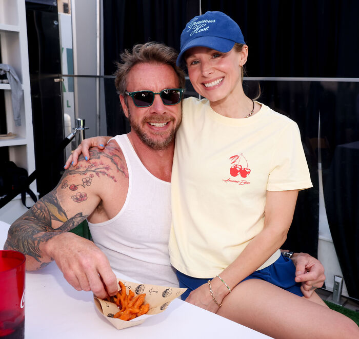 Kristen Bell sitting on Dax Shepard's lap while eating snacks