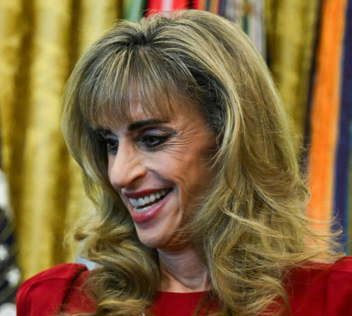Smiling portrait of a billionaire spotted at White House event with blonde hair and red dress. Smiling portrait of a billionaire spotted at White House event with blonde hair and red dress.