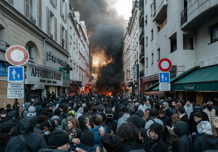 Crowd gathered on Paris street with smoke from fire during France riots