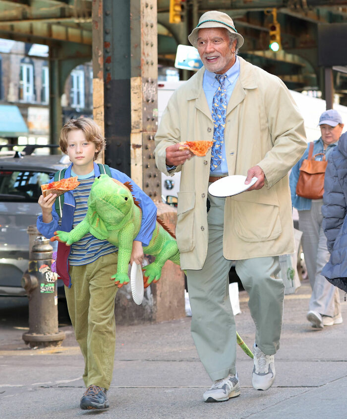 Dwayne Johnson undergoing a dramatic transformation on set with prosthetics, carrying pizza with a boy.