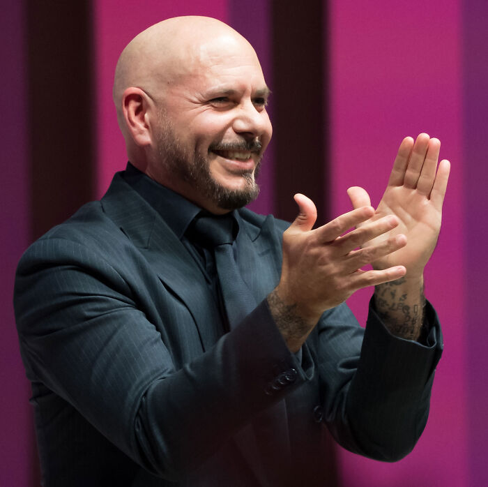 Pitbull smiling and clapping at an event while wearing a suit Pitbull smiling and clapping at an event while wearing a suit