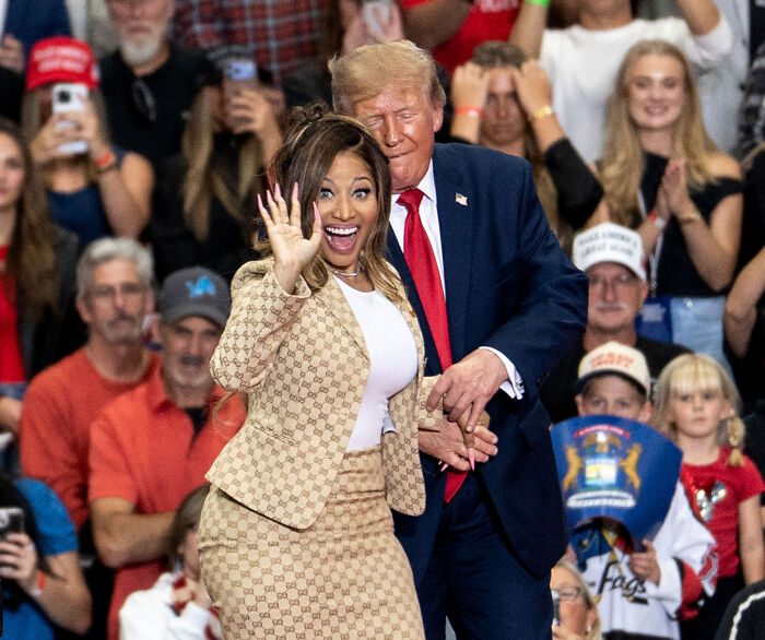 Nicki Minaj smiling and waving while on stage with Donald Trump at a rally. Nicki Minaj smiling and waving while on stage with Donald Trump at a rally.