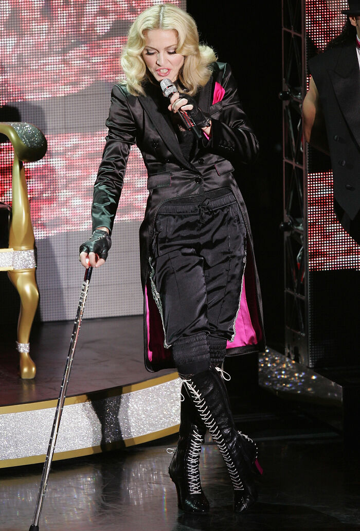 Pop singer Madonna performing on stage while stylishly holding a cane as a performance mobility aid.