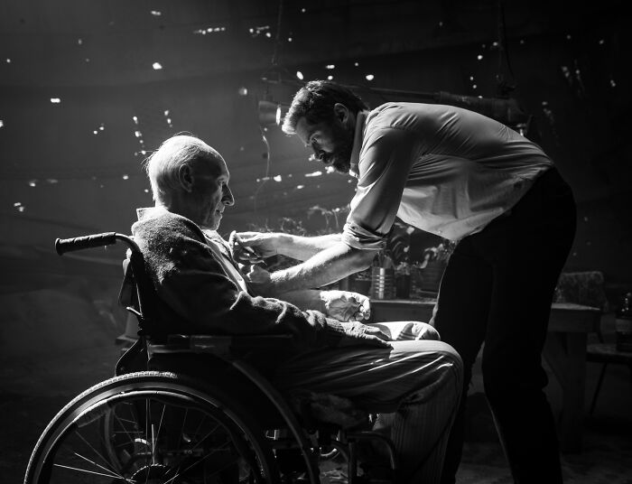 Black and white photo of Hugh Jackman tending to Patrick Stewart sitting in a wheelchair. Black and white photo of Hugh Jackman tending to Patrick Stewart sitting in a wheelchair.
