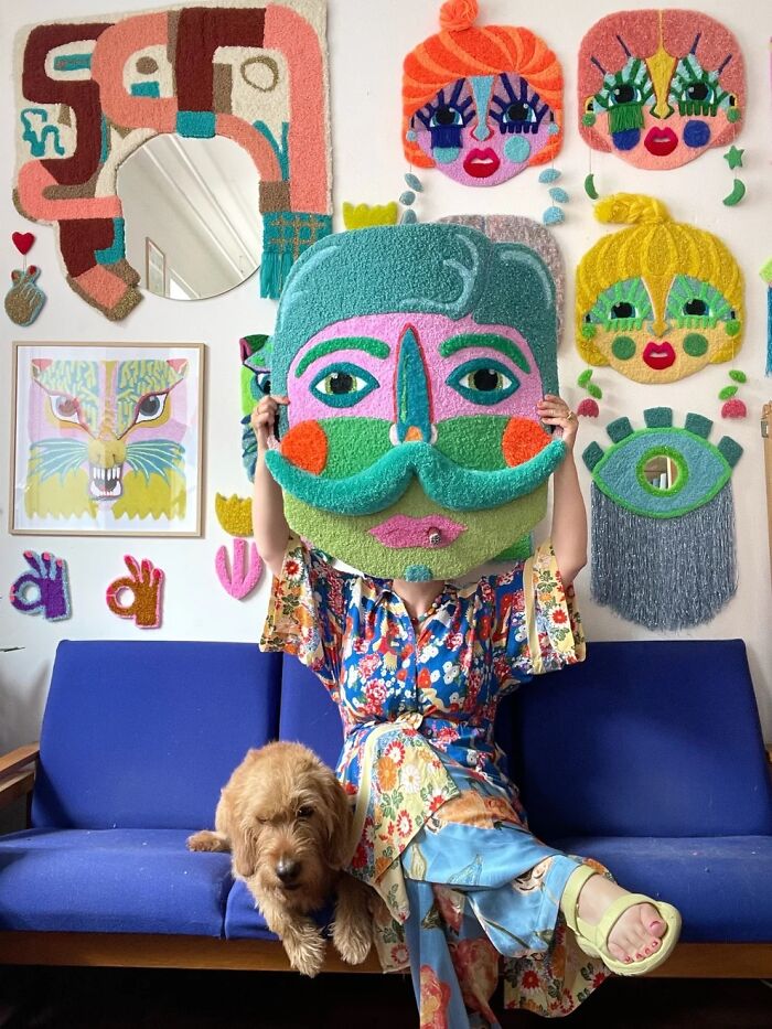 Ina Dyreborg holding a large tufted face rug on a blue sofa