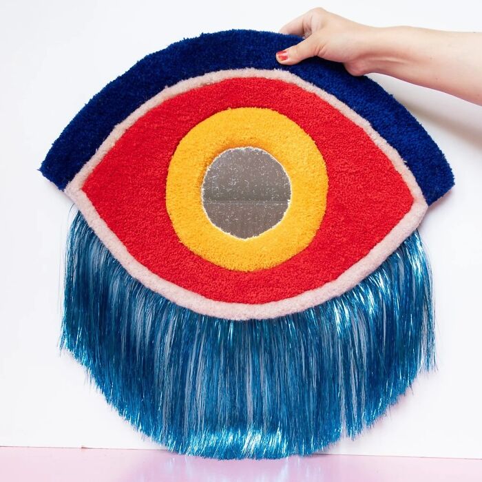 Tufted eye-shaped wall hanging with a mirror center by Ina Dyreborg