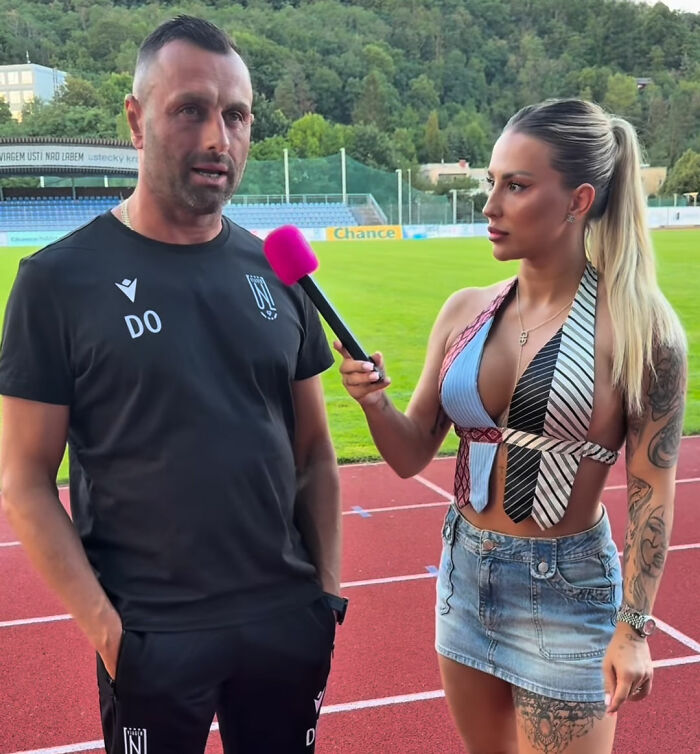 Coach speaking to female reporter with pink microphone on running track