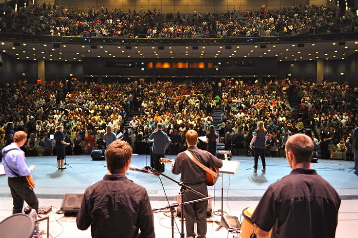 View from the stage of a band performing in front of a packed auditorium of lesser-known cults followers.