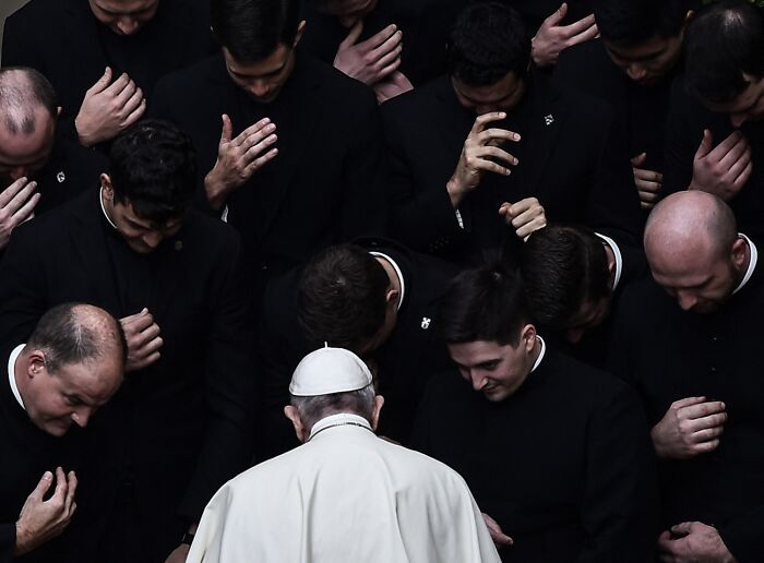 Group of men in black with leader in white, somber moment, best pics Siena International Photo Awards 2026