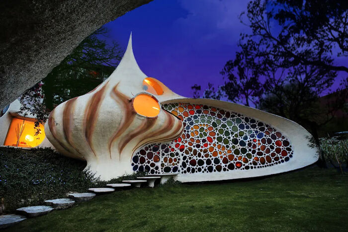 Strange shell-shaped building with round windows and artistic architecture at night