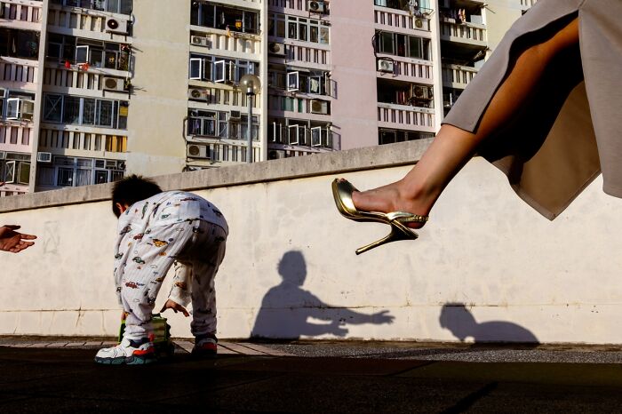 Child playing outside with adult wearing high heel shoes in city, best pics 2026