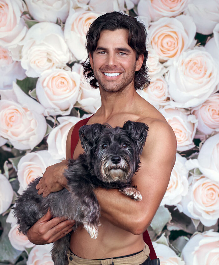 Smiling Australian firefighter holding a dog with floral backdrop for 2027 firefighter calendar