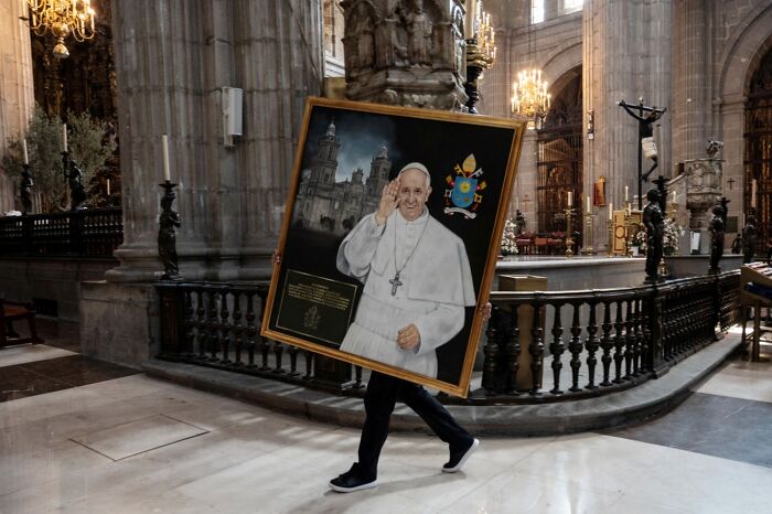 Person carrying large framed portrait inside cathedral at Siena International Photo Awards