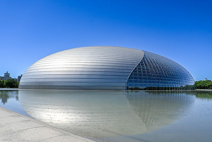 Oval glass and metal building reflecting on water strange buildings