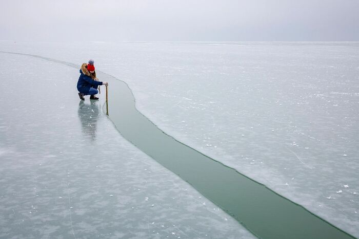 A researcher measuring a fissure on an ice surface, representing entry in OurNature Environmental Photo Awards.