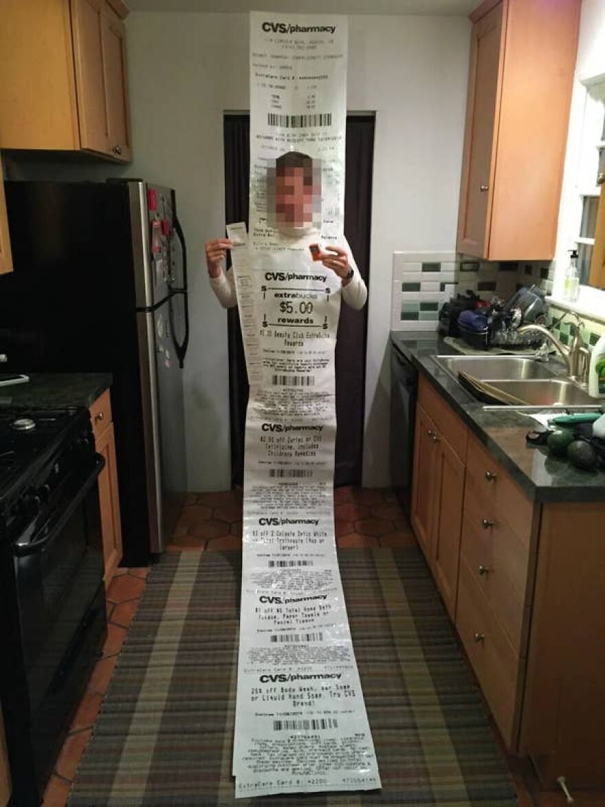 Person wearing a creative long CVS receipt Halloween costume standing in a kitchen.