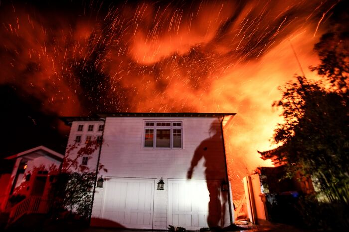 Housefire at night with bright flames and shadow of person on wall