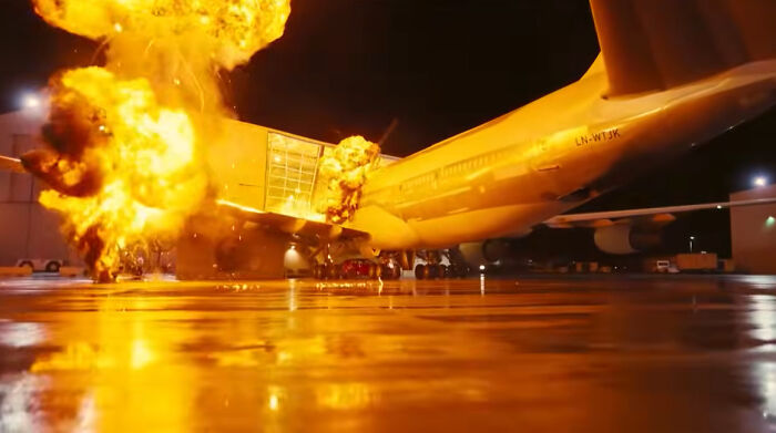 An action movie scene depicting a massive airplane explosion with fiery movie props.