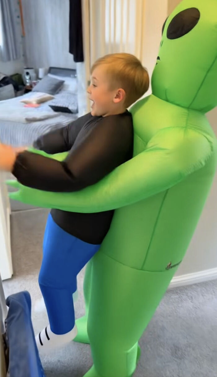 A boy wearing an inflatable green alien abduction outfit as a creative low-effort Halloween costume.