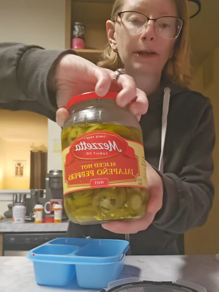 Woman holding jar of pickled jalapeno peppers for lunch Woman holding jar of pickled jalapeno peppers for lunch