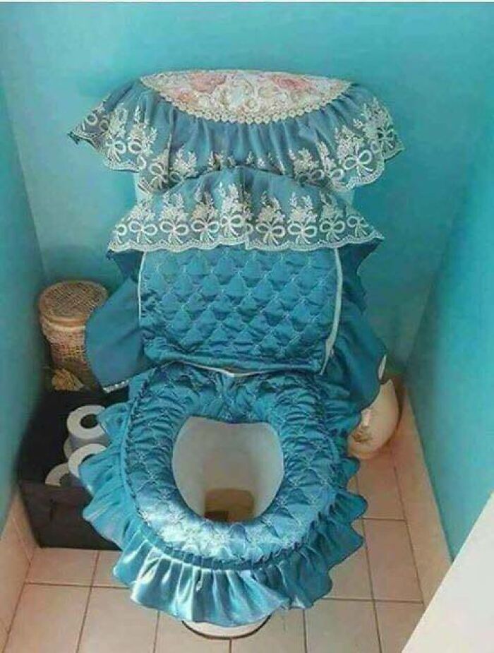 Toilet with elaborate blue cushioned cover and lace decoration in bathroom corner