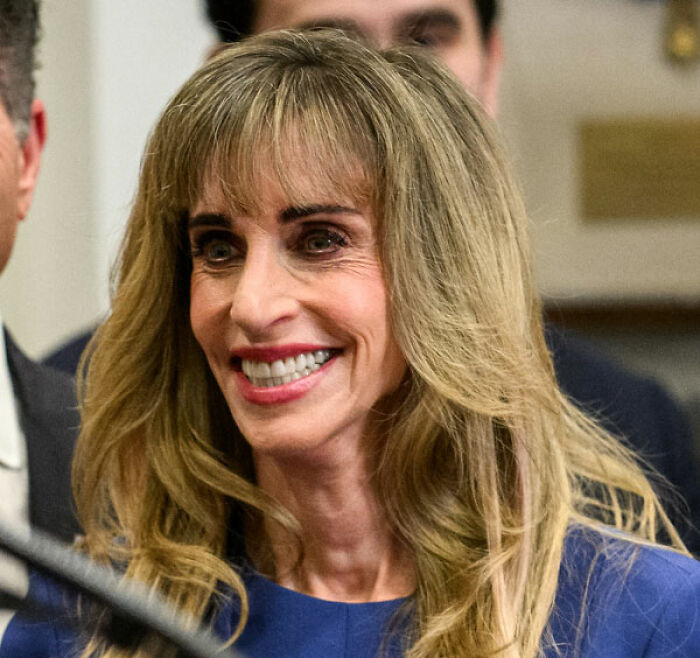 Smiling woman with long hair linked to MAGA face portrait controversy Smiling woman with long hair linked to MAGA face portrait controversy