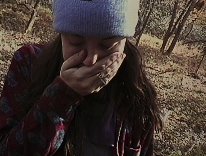 A person covering their face in the woods, recalling shocking moments like famous PR stunts.