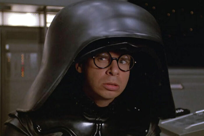 Rick Moranis in Spaceballs wearing a large helmet, depicting famous stars in iconic film roles.