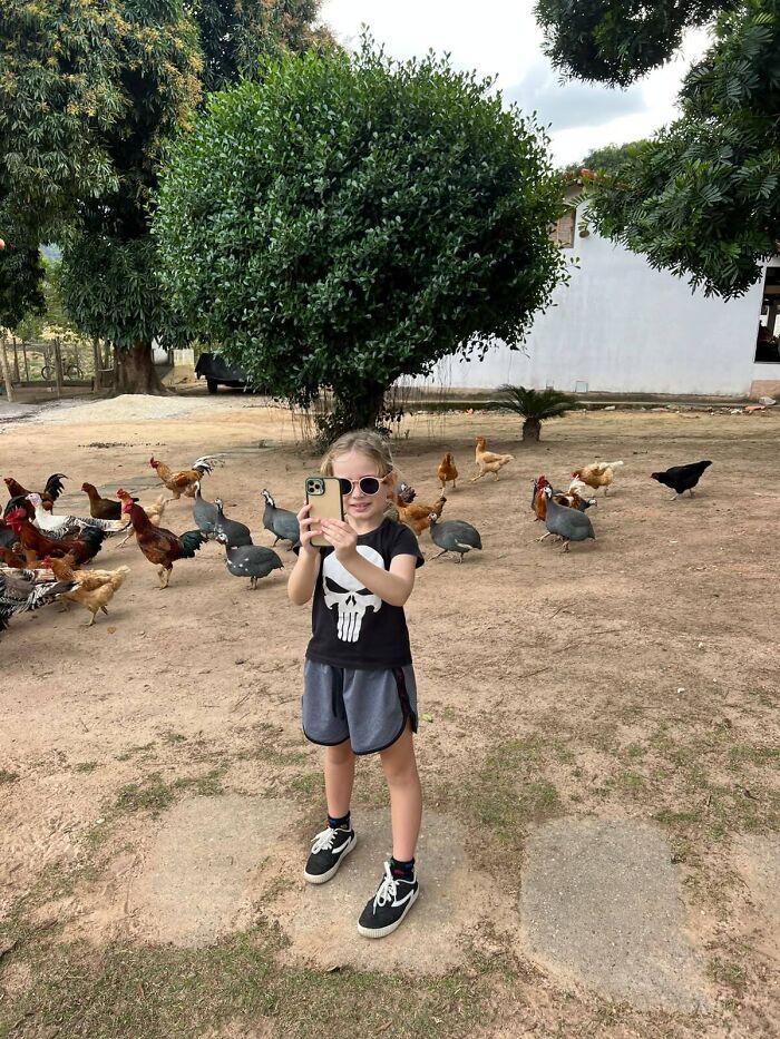 An animal trainer daughter taking photos in a yard filled with poultry